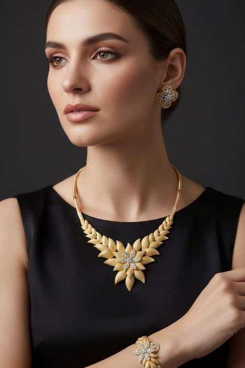 Gold jewelry set featuring a necklace and matching earrings displayed on a red velvet jewelry box, set against a black fabric background.